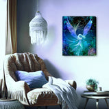 Mystical angel artwork in deep blues, purple, teal and black with an art nouveau feathery foliage border by Primal Painter printed as a stretched canvas hanging next to a chair