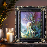 Fantasy Art Print of a fairy with long white hair and wispy wings in a garden of teal and blue foliage with art nouveau flourishes called Fairy Garden by Primal Painter. Displayed in a black frame on a shelf