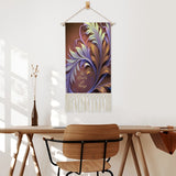 Fringed canvas wall hanging featuring artwork by Primal Painter of art nouveau foliage in rust, orange, and violet with the affirmation Be Kind to All Things hanging over a table