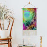 fringed canvas wall hanging featuring rainbow artwork of a flower child by Primal Painter and the Reiki Principles hanging by a chair